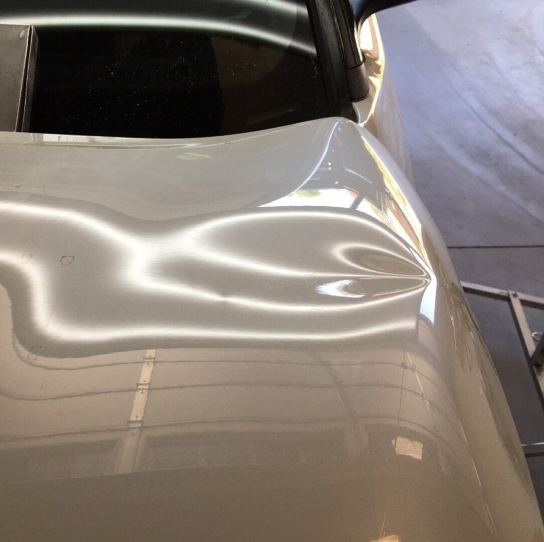 Silver car with crease dent before paintless dent repair