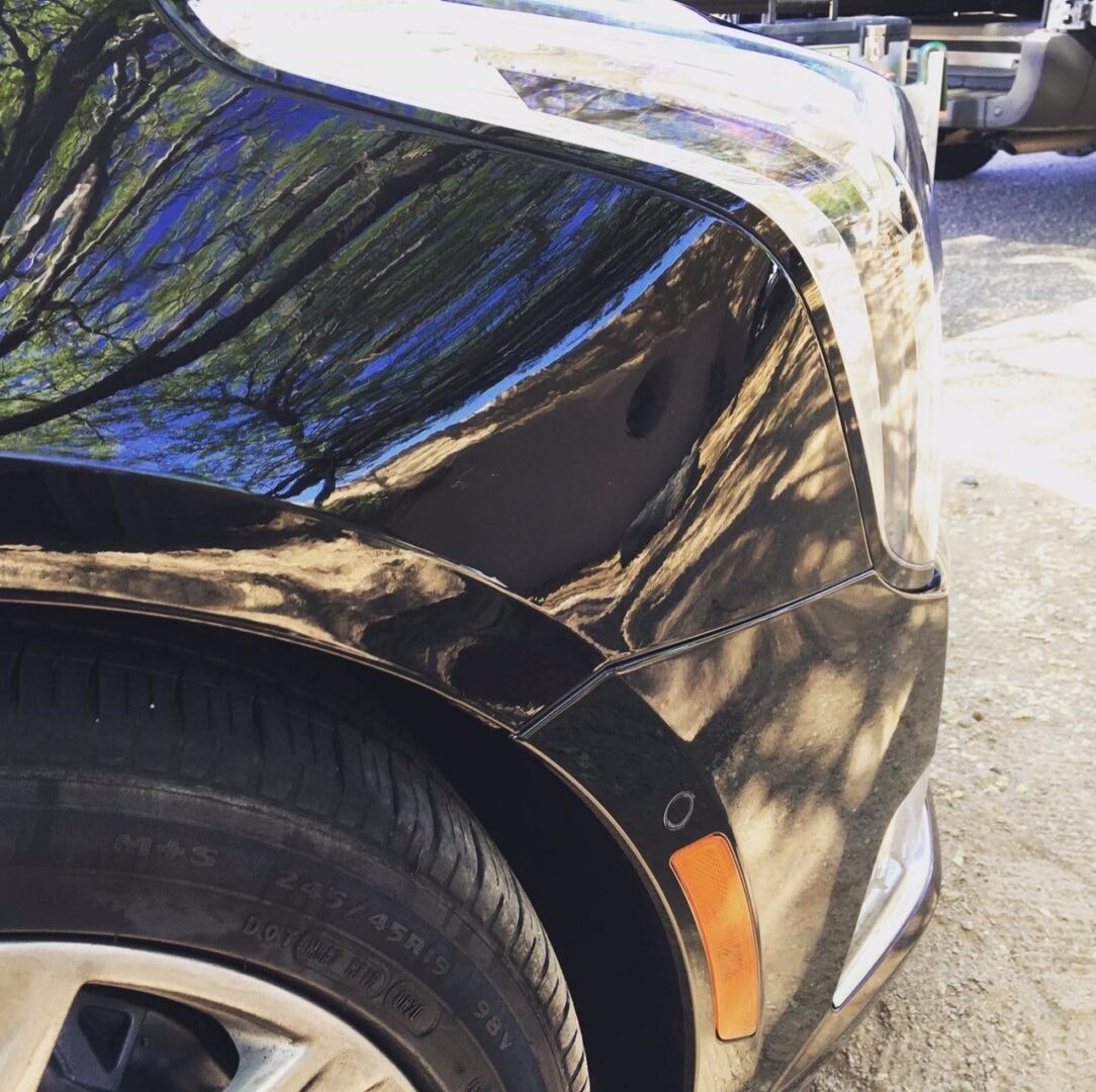 Black car fender smooth and restored after paintless dent repair