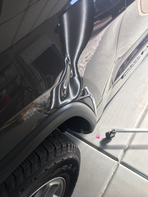 Silver SUV fender with large crease dent before paintless dent repair