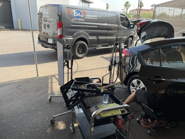 PDR tool cart set up outdoors next to vehicle with Elite Dent Removal van in background